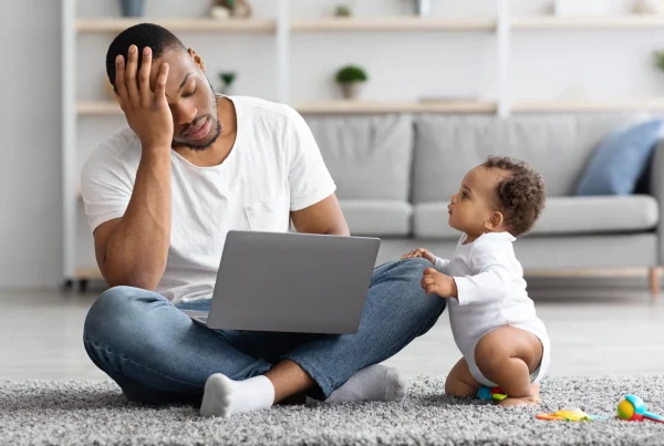 Stressed businessperson juggling a baby and laptop, symbolising high-maintenance websites.
